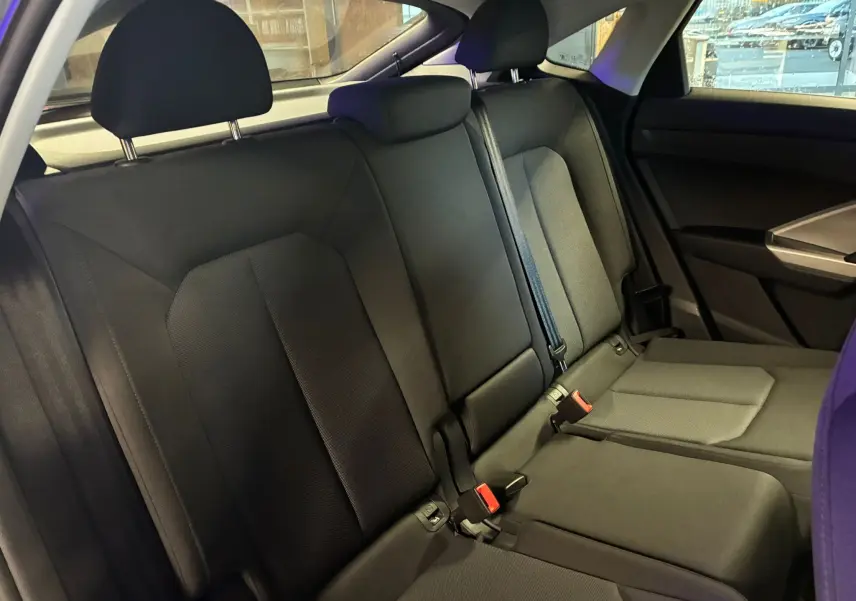 Vue intérieure des sièges arrière noirs de l'Audi Q3 Sportback 2021, avec ceinture de sécurité et appuie-têtes visibles.