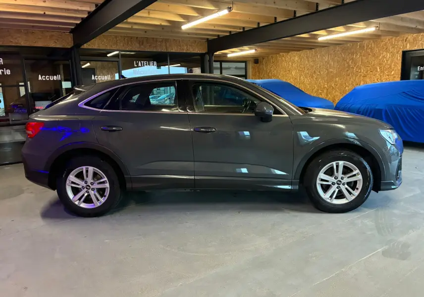 Vue de profil côté gauche d'un Audi Q3 Sportback gris 2021 avec jantes aluminium 17 pouces dans un garage.