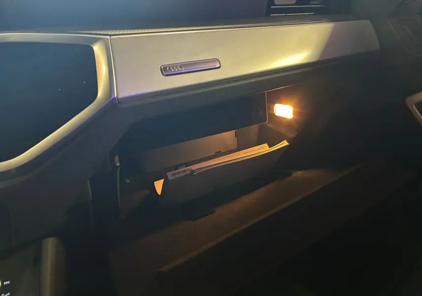 Vue intérieure du vide-poche éclairé côté passager de l'Audi Q3 Sportback 2021 avec bande décorative argent micrométallique.