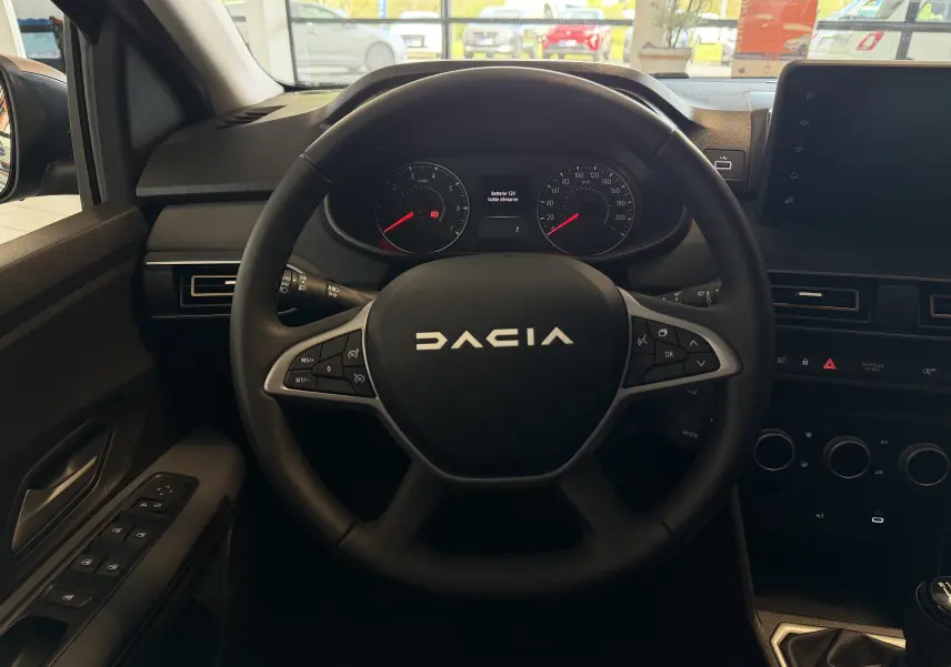 Vue centrée sur le volant noir du Dacia Jogger 2026, avec tableau de bord et commandes visibles en intérieur.
