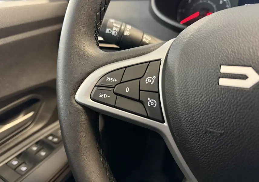 Gros plan sur le volant noir de la Dacia Jogger 2026, montrant les commandes de régulateur de vitesse côté gauche.