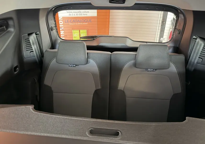 Vue intérieure arrière du Dacia Jogger 2026, sièges gris avec appuie-têtes et ceintures visibles, arrière vitré et cache-bagages.