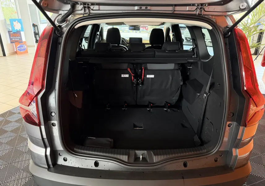 Vue arrière du coffre ouvert du Dacia Jogger gris schiste métal, montrant les sièges arrière rabattus et l'intérieur spacieux.