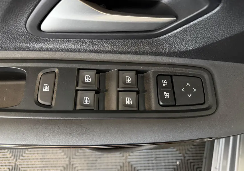 Gros plan sur les commandes de lève-vitres et réglage des rétroviseurs côté conducteur du Dacia Jogger gris schiste métal.
