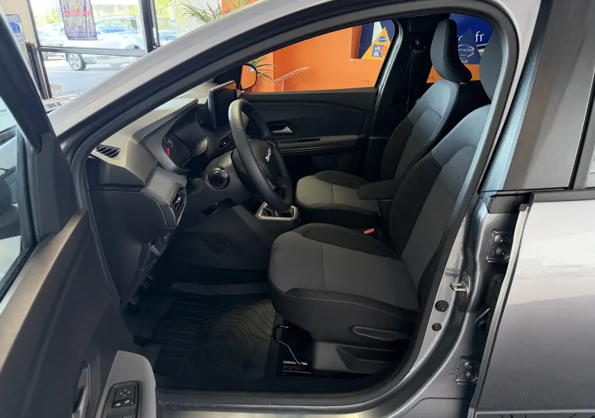 Vue intérieure côté conducteur du Dacia Jogger gris schiste métal 2026, avec sièges tissu noir et volant multifonction.