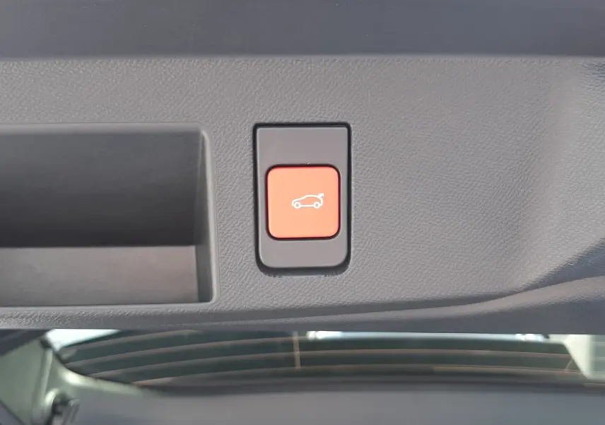 Bouton rouge de hayon électrique vu en gros plan à l'intérieur du coffre du Citroën C5 Aircross vert Astoria.