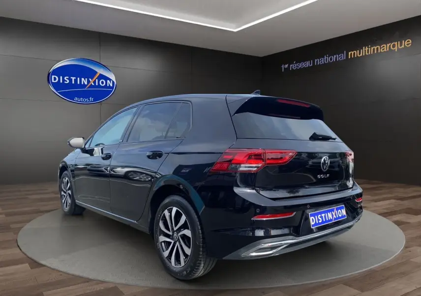 Volkswagen Golf VIII noire vue 3/4 arrière droit, avec vitres surteintées et jantes alliage en showroom.