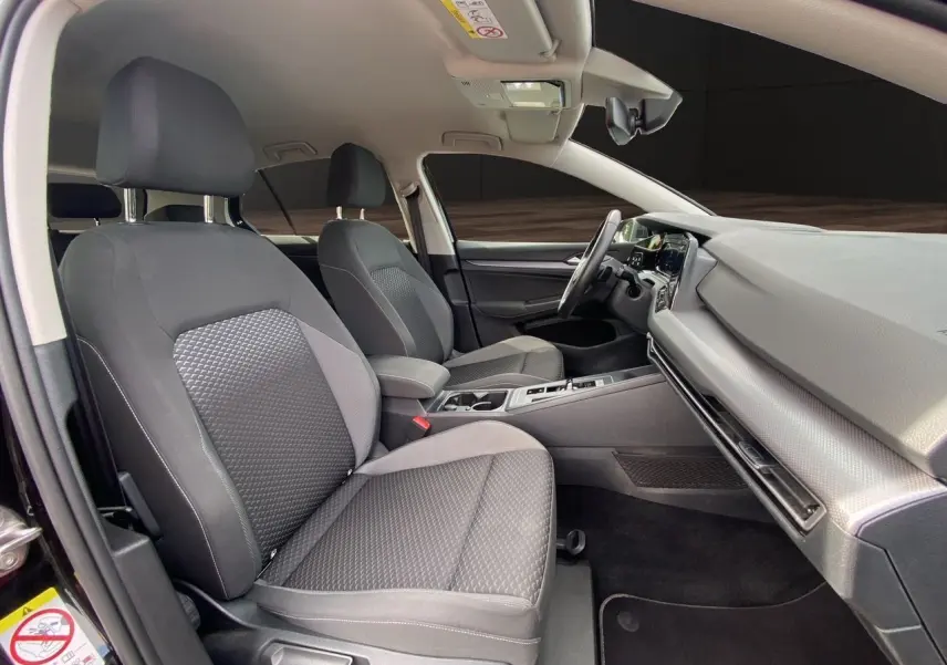 Intérieur de la Volkswagen Golf VIII essence 2022, vue côté droit sur sièges tissu noir et tableau de bord moderne.