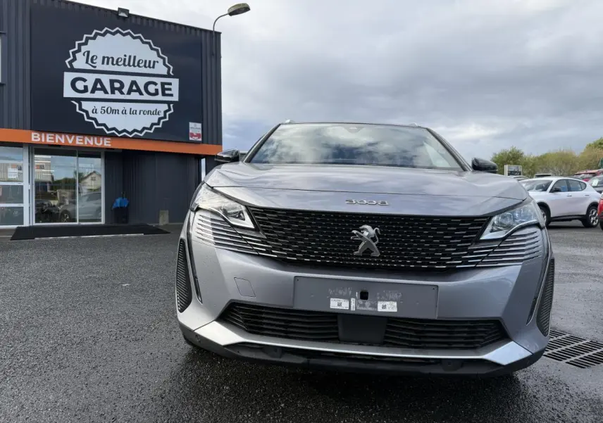 Vue frontale d'un Peugeot 3008 gris métallisé avec calandre noire et logo lion chromé visible au garage.