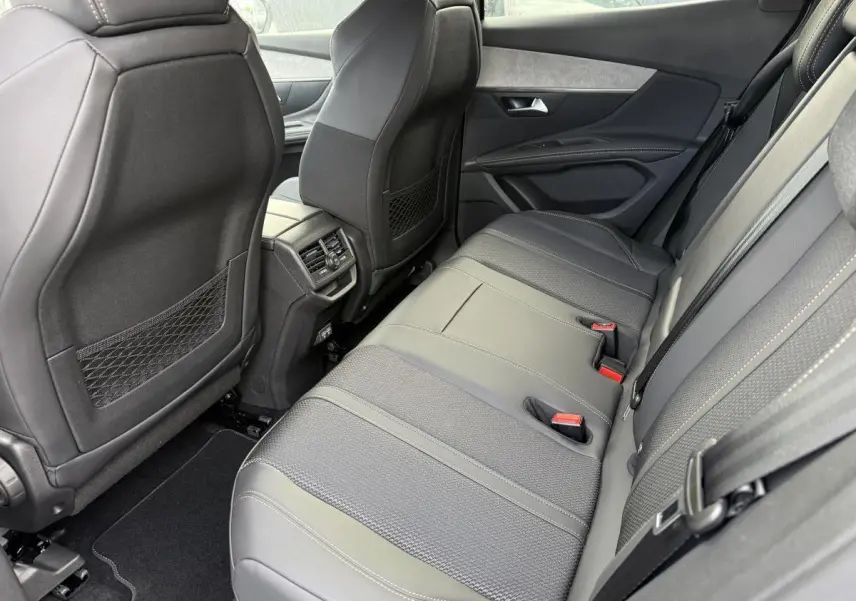 Vue latérale droite de la banquette arrière en cuir gris et tissu du Peugeot 3008 Hybrid 2023 avec aérateurs centraux.