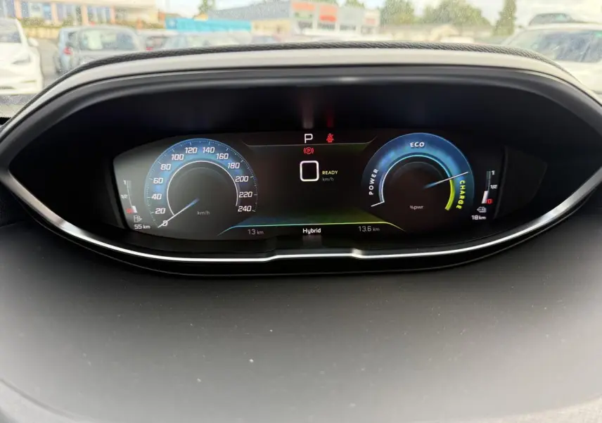 Tableau de bord numérique du Peugeot 3008 Hybrid 2023 affichant vitesse, mode hybride et jauges d'énergie en vue frontale.
