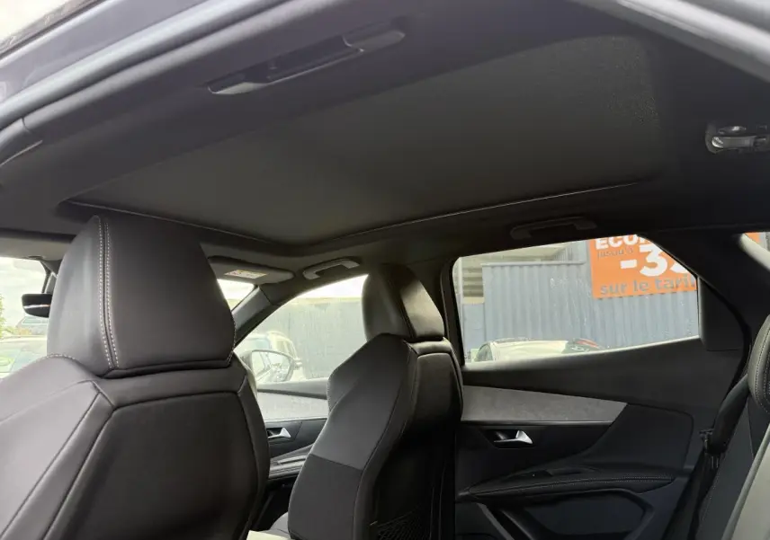 Vue intérieure côté droit du Peugeot 3008 Hybrid 2023 avec sièges en cuir noir et toit ouvrant panoramique fermé.