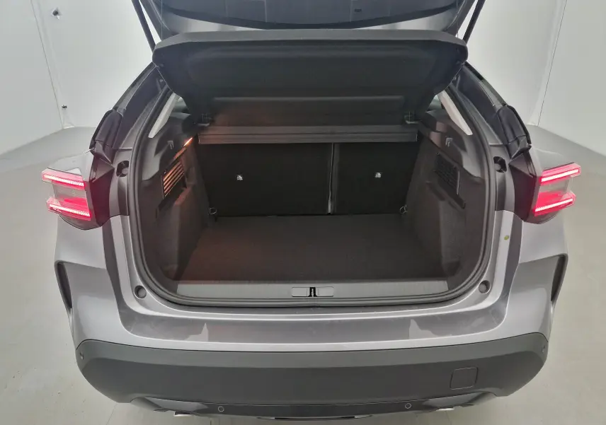 Coffre ouvert vu de l'arrière d'une Citroën C4 2025 gris Mercury et noir avec feux arrière allumés.