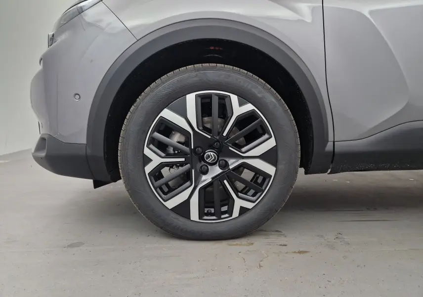 Gros plan sur la roue avant gauche de la Citroën C4 2025 gris Mercury/noir avec jante alliage noire et argentée.