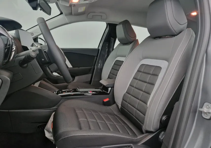Vue intérieure côté gauche de la Citroën C4 2025, sièges bi-matière gris et noir avec console centrale moderne.
