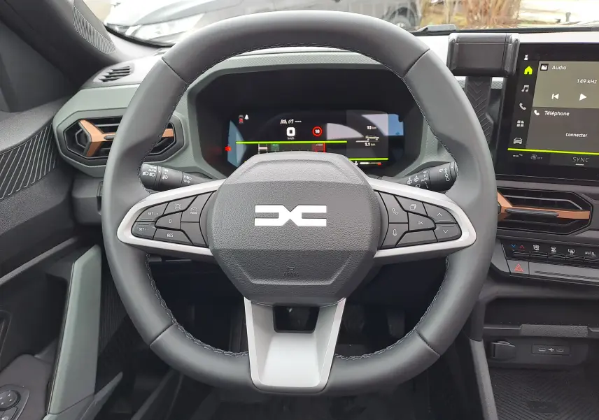 Vue intérieure centrée sur le volant noir du Dacia Bigster 2025 avec tableau de bord numérique et écran tactile.