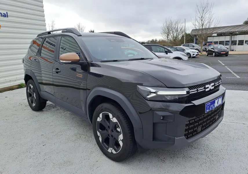 Vue 3/4 avant droit du Dacia Bigster noir nacré avec rétroviseurs couleur bronze et jantes bi-ton distinctives.