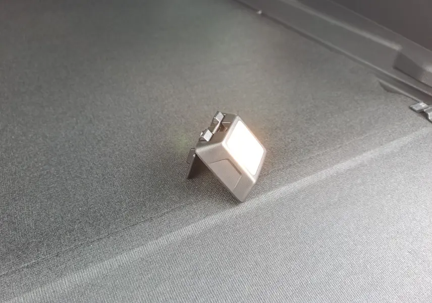 Gros plan sur la lumière intérieure allumée dans le coffre du Dacia Bigster noir nacré, mettant en valeur le revêtement gris.