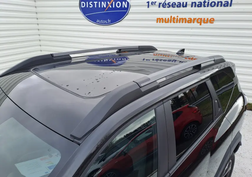 Vue en plongée du toit noir nacré du Dacia Bigster 2025, mettant en valeur le toit ouvrant et les barres de toit.