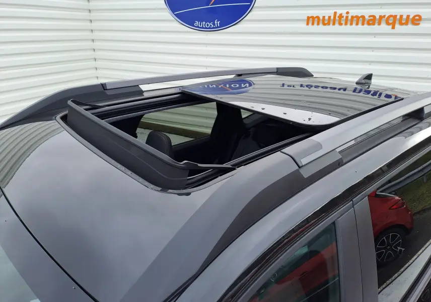 Toit ouvrant panoramique ouvert sur le dessus d’un Dacia Bigster noir nacré, vue en plongée depuis l’avant droit.