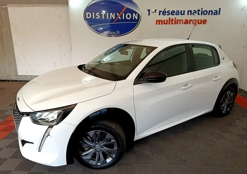 Peugeot 208 électrique blanche vue en 3/4 avant droit, avec jantes foncées et rétroviseurs noirs.