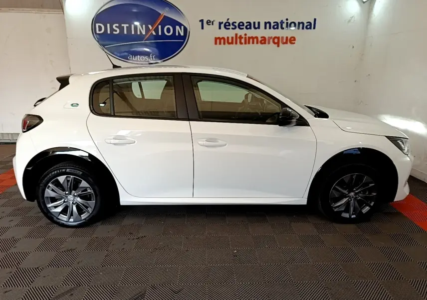 Peugeot 208 électrique blanche vue de profil côté droit, avec jantes alliage et logo "e" sur l'aile arrière.