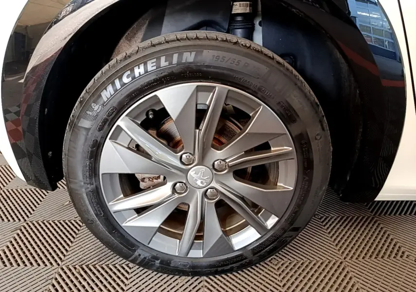 Gros plan sur la roue avant droite blanche de la Peugeot 208 électrique avec jante alliage et pneu Michelin.