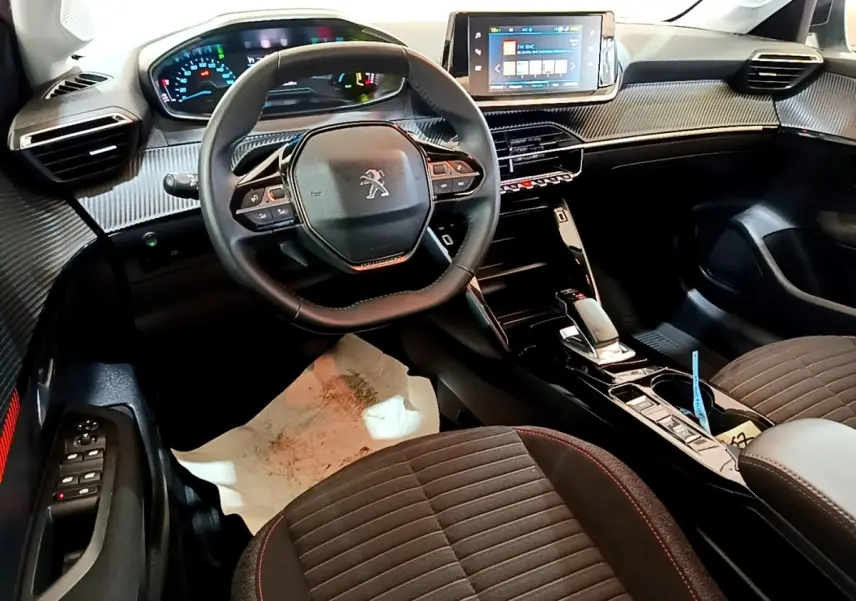 Intérieur de la Peugeot 208 électrique vue côté conducteur, volant cuir, tableau de bord numérique et écran tactile central.