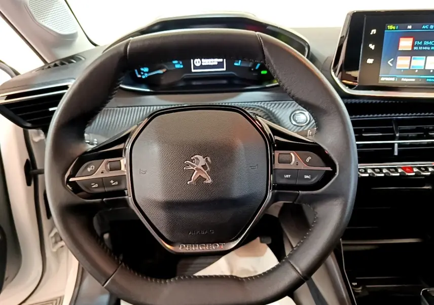 Vue intérieure centrée sur le volant cuir multifonctions d’une Peugeot 208 électrique blanche avec tableau de bord digital.