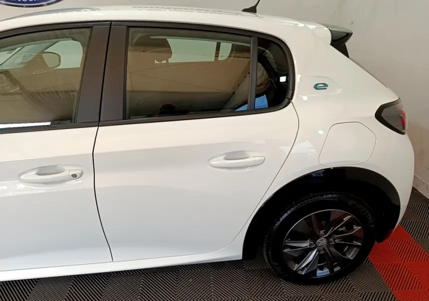 Vue latérale droite d'une Peugeot 208 électrique blanche, mettant en valeur la porte arrière et la jante noire.