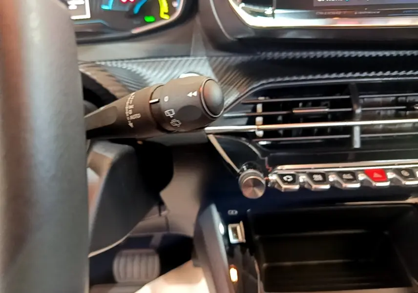 Gros plan intérieur sur la commande d’essuie-glace et la console centrale noire du tableau de bord de la Peugeot 208 électrique.