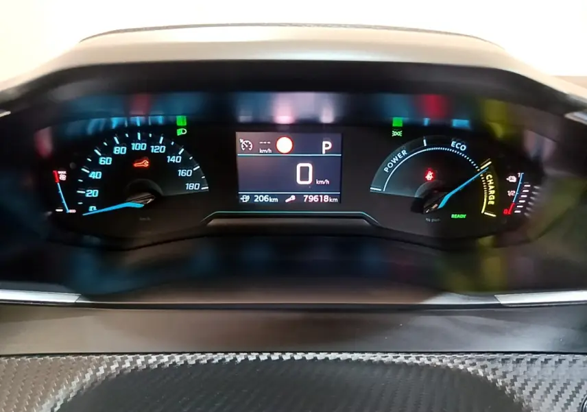 Vue rapprochée du tableau de bord numérique de la Peugeot 208 électrique, affichant la vitesse à 0 km/h et l'autonomie restante.