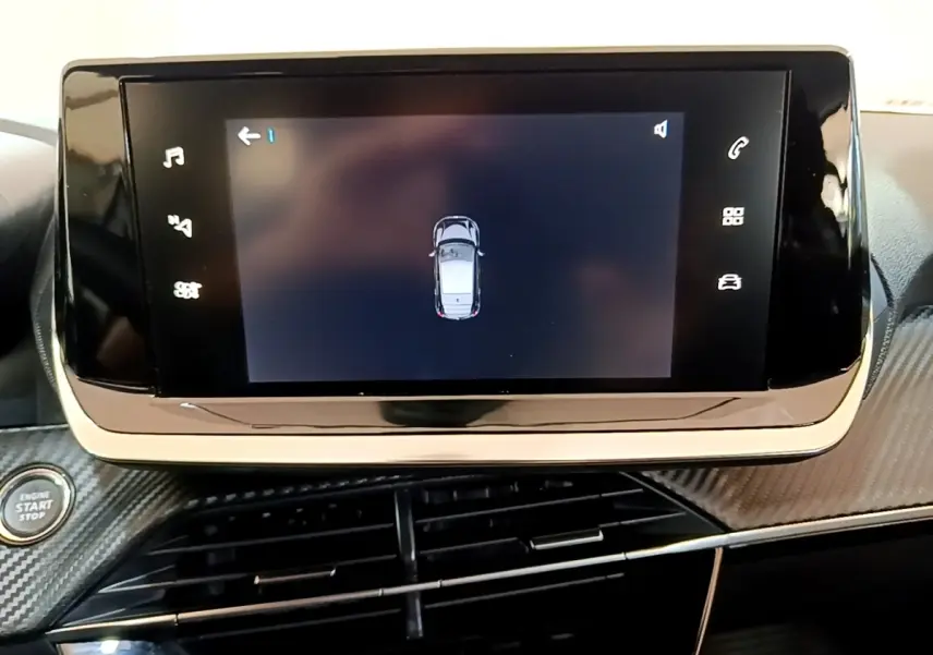 Écran tactile central affichant la vue de dessus du véhicule, tableau de bord noir avec finition carbone dans une Peugeot 208 électrique.