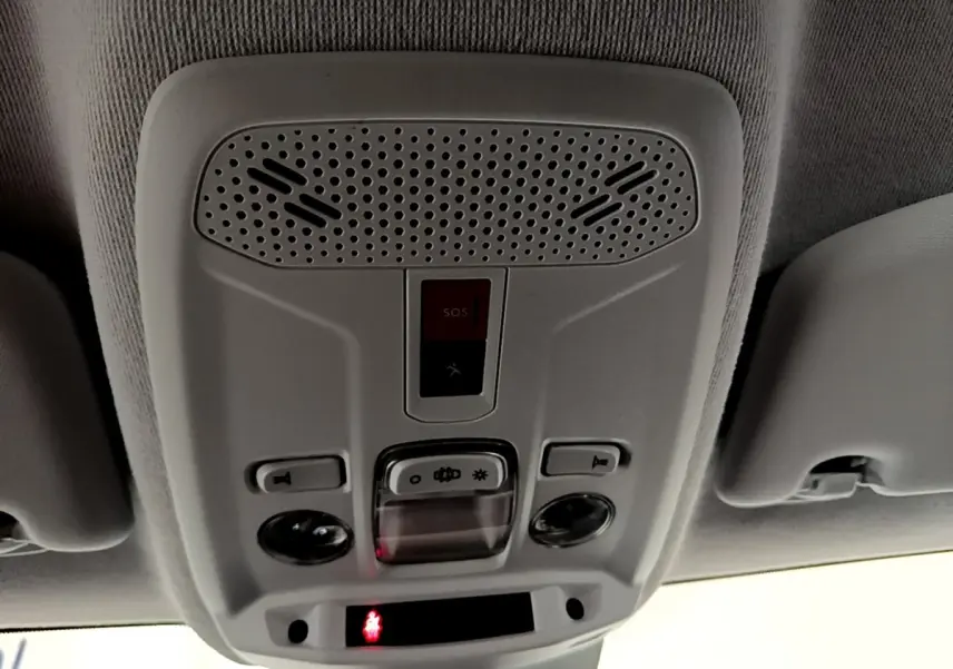 Vue intérieure du plafonnier gris clair avec boutons d’éclairage et bouton SOS dans une Peugeot 208 électrique blanche.