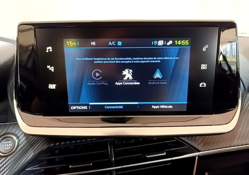 Écran tactile central affichant Apple CarPlay et Android Auto dans le tableau de bord d’une Peugeot 208 électrique blanche.