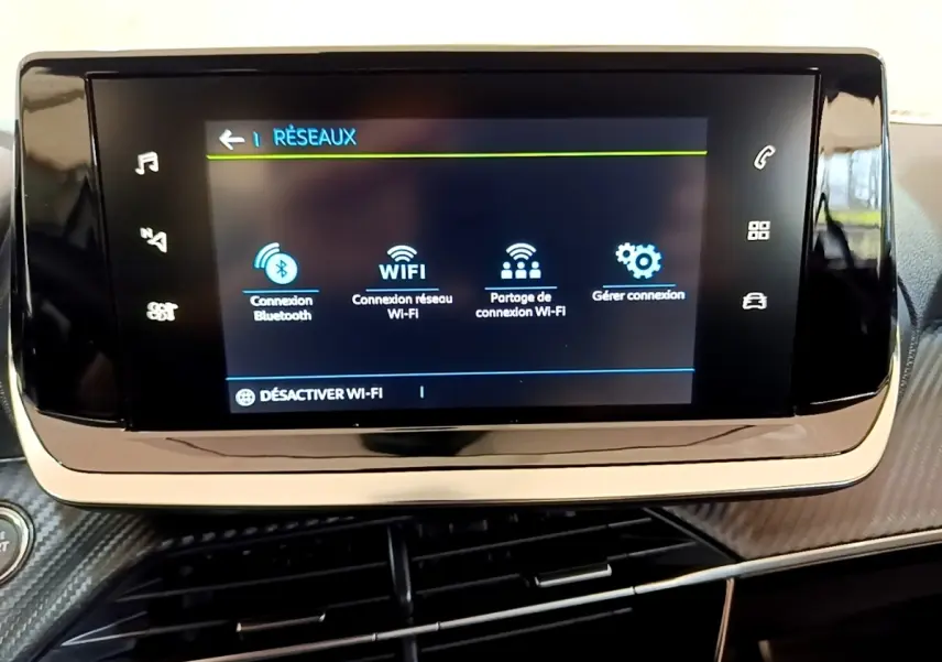 Écran tactile central affichant les options réseau dans l’habitacle du Peugeot 208 électrique blanc, vue intérieure frontale.