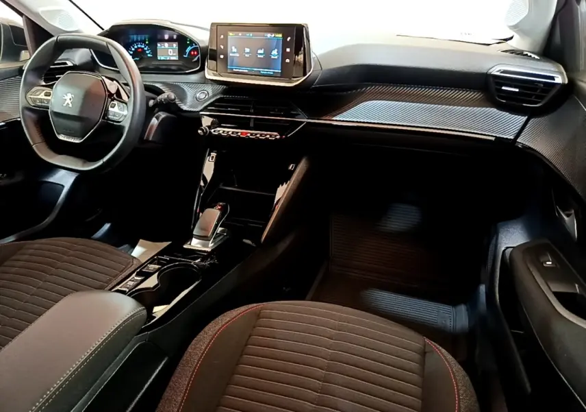 Vue intérieure avant de la Peugeot 208 électrique 2022, tableau de bord noir avec écran tactile central et volant compact cuir.