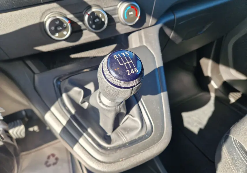 Gros plan sur le levier de vitesses manuel du Renault Kangoo 2023, avec tableau de bord et commandes de climatisation visibles.
