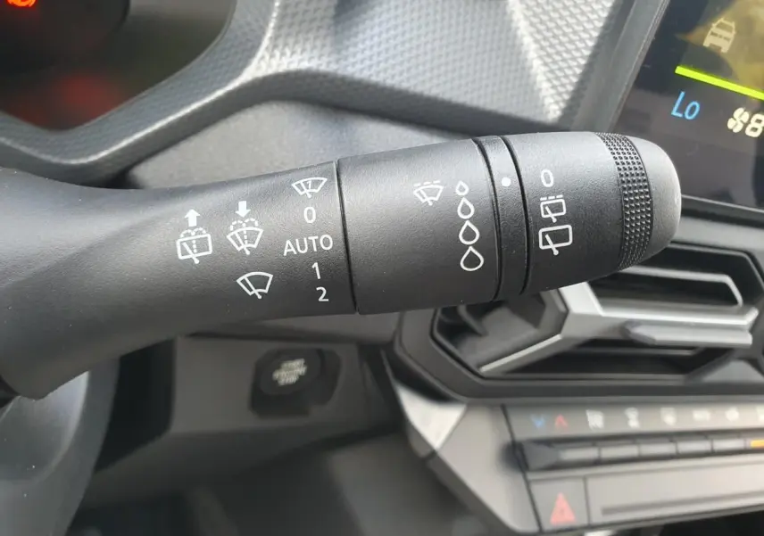 Gros plan sur la commande d’essuie-glace à gauche du volant du Dacia Duster gris schiste, avec tableau de bord en arrière-plan.