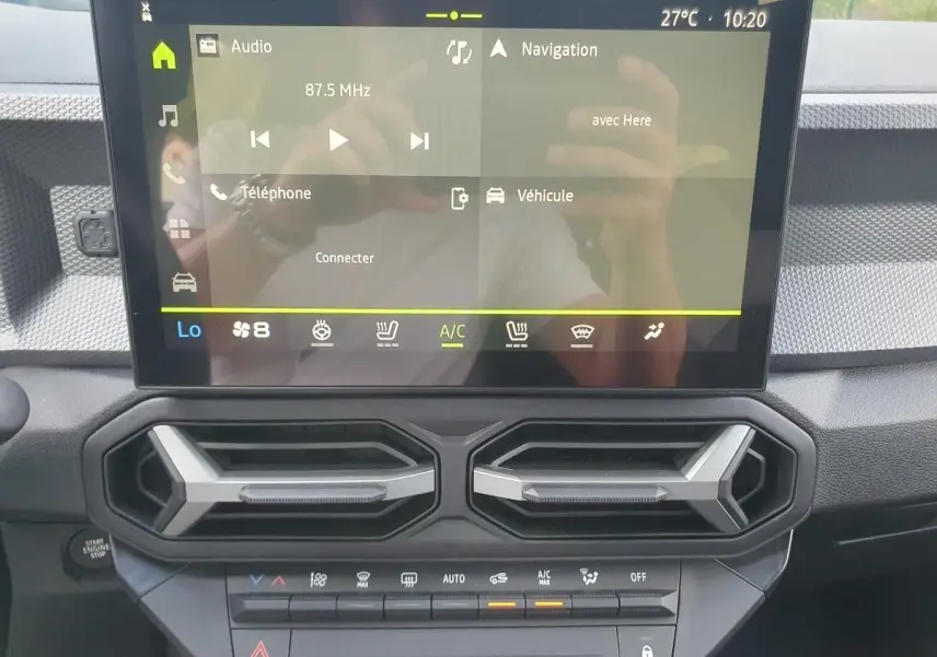 Vue rapprochée de la console centrale du Dacia Duster 2026 avec écran tactile et aérateurs hexagonaux noirs.