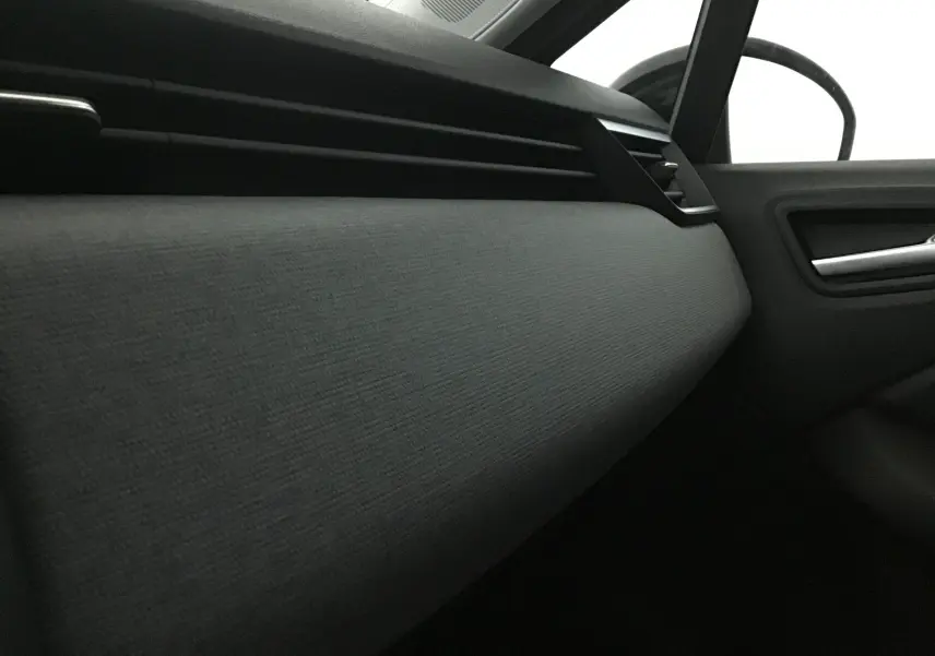 Vue rapprochée de la planche de bord côté passager de la Renault Clio V gris schiste avec aérateurs horizontaux noirs.