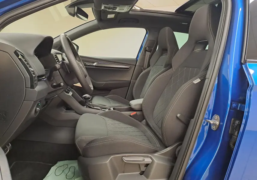 Intérieur côté conducteur du Skoda Karoq Bleu RS 2025, sièges sport et toit panoramique ouvert visible.