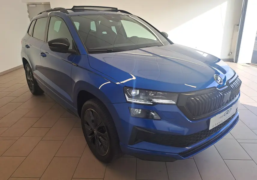 Skoda Karoq Bleu RS en 3/4 avant droit, avec calandre noire et toit ouvrant panoramique visible.