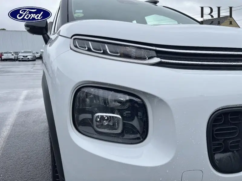 Gros plan sur l'avant gauche d'une Citroën C3 Aircross blanche Natural White avec ses phares distinctifs et calandre noire.