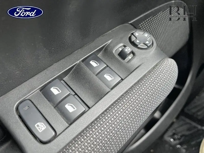 Gros plan sur les commandes de vitres électriques et rétroviseurs côté conducteur d'une Citroën C3 Aircross blanche.