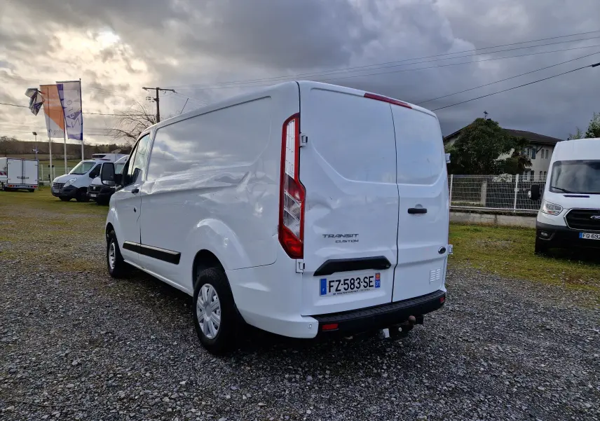 Vue arrière ouverte du fourgon blanc Ford Transit Custom L1H1 avec aménagements en bois sur les côtés du coffre.
