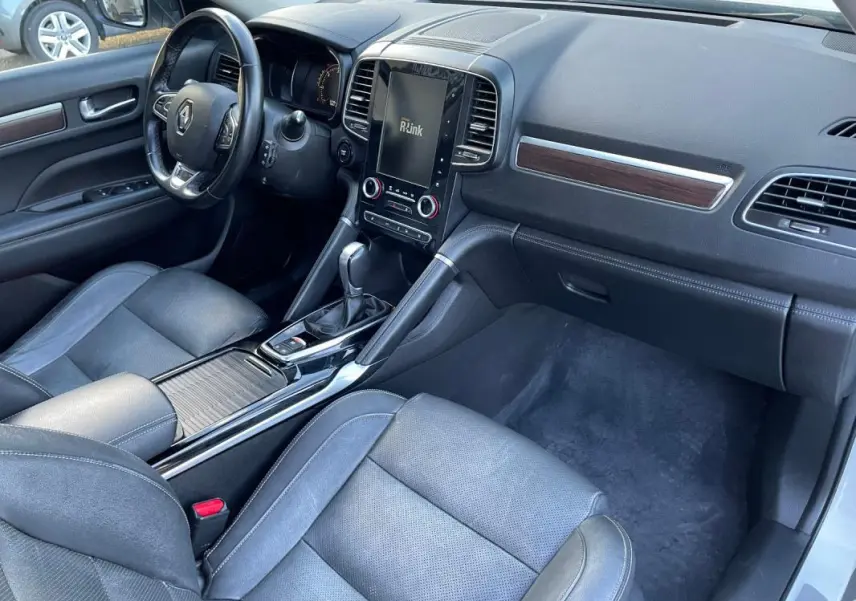 Vue intérieure côté passager du Renault Koleos blanc 2019, mettant en valeur le tableau de bord et la console centrale avec écran tactile.
