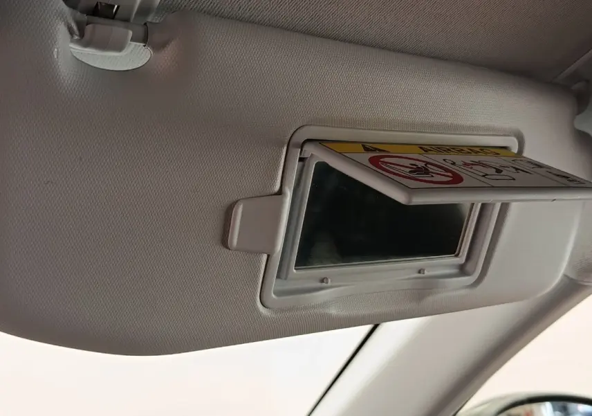 Détail du pare-soleil côté conducteur avec miroir de courtoisie et avertissement airbag dans une Peugeot 208 noire.