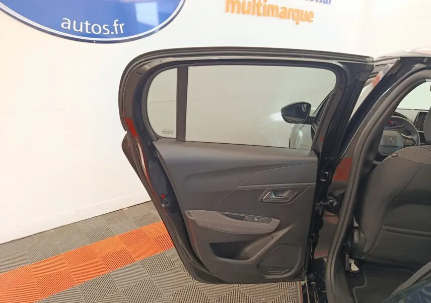 Vue intérieure de la porte arrière gauche ouverte d’une Peugeot 208 noire, montrant les détails du panneau de porte.