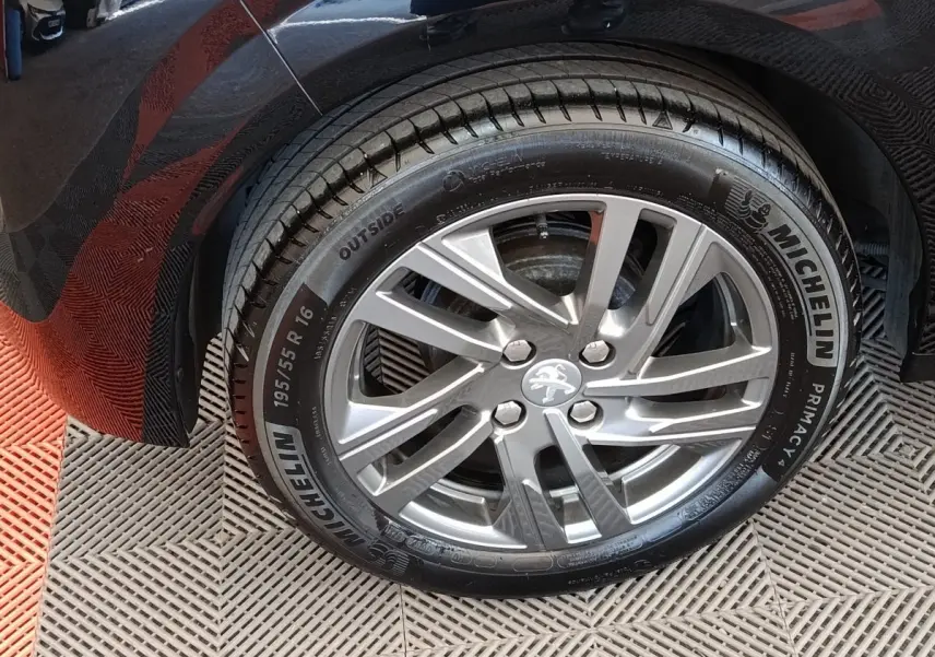 Gros plan sur la roue arrière gauche d'une Peugeot 208 noire, jante alliage argentée et pneu Michelin.